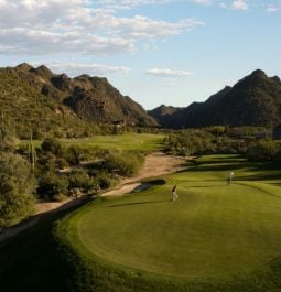 golfers on a golf course surrounded by mountains