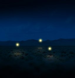 three orbs of light floating in desert at night
