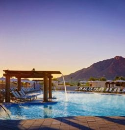 resort pool at sunset with fountain and mountain behind
