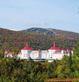 new england resort atop a hill surrounded by mountains and forest