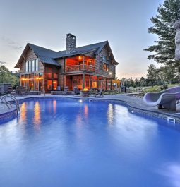 swimming pool at dusk in front of log cabin