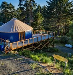 blue yurt at night overlooking trees and coast