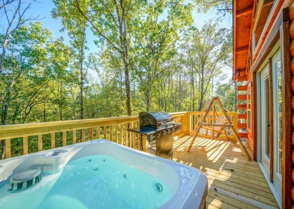 cabin deck with hot tub, swing, and grill