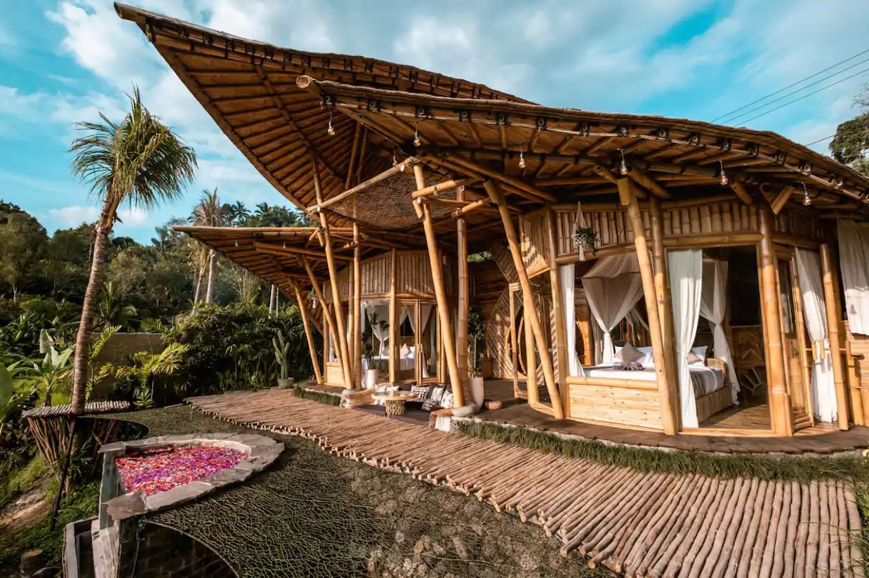 The exterior of an open-air bamboo house in Bali with an outdoor hot tub