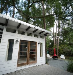 Exterior of a modern tiny home in Gainesville surrounded by lush landscaping and tall trees