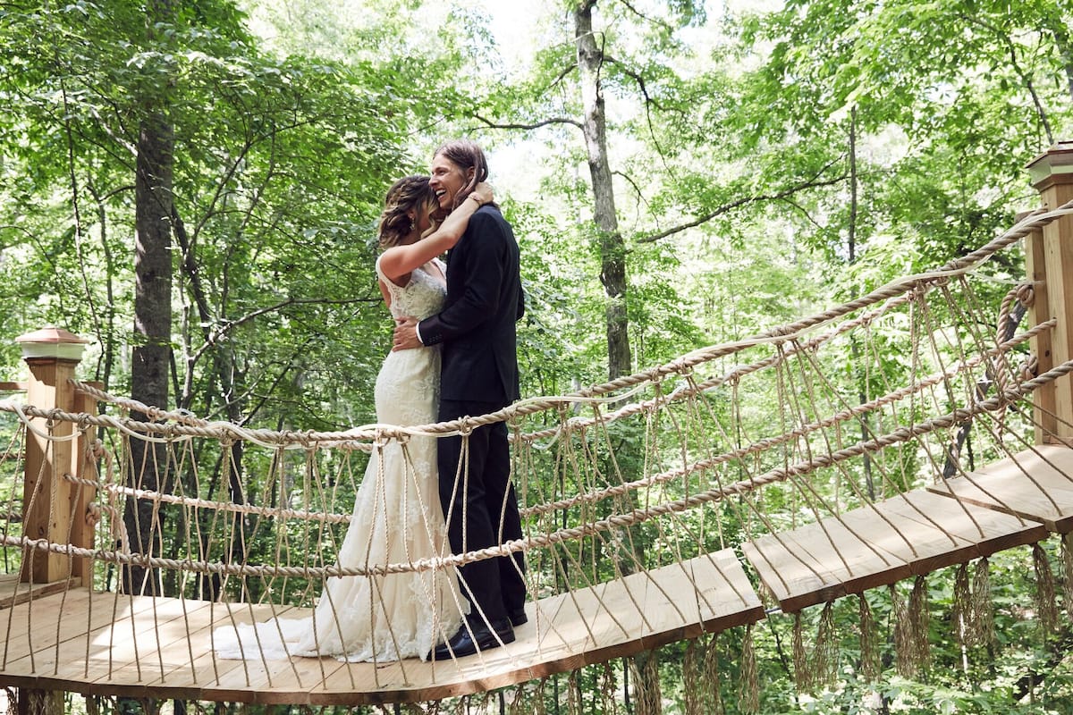 couple on a swinging bridge in the trees