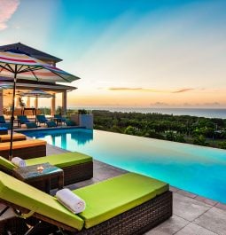 Rainbow hued sunset from infinity pool with green sunbeds