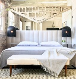 Loft sleeping area with bed, padded headboard, throw blankets and decorative ceiling adornment