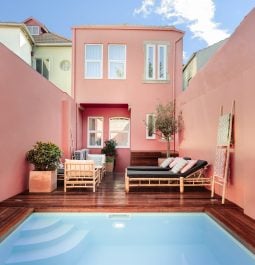Pastel pink villa with pool in front and square building behind