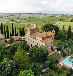 Birds eye view of stately Italian villa with swimming pool surrounded by trees