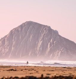 Lone surfer and a giant rock in the ocean