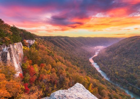 fall foliage on mountains surrounding river gorge at sunset