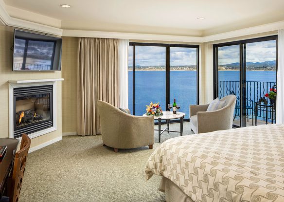 Hotel room with panoramic windows overlooking the ocean and a fireplace