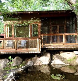 cabin on the rocks by a river with a deck
