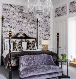 purple-themed bedroom at luxury hotel with patterned wallpaper and four poster bed