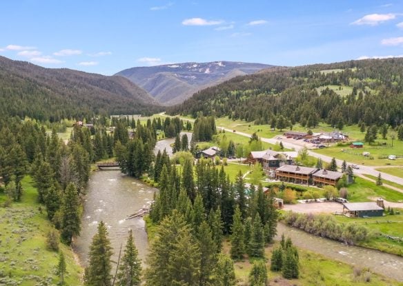aerial view of riverside lodge surrounded by mountains