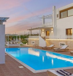 Exterior of a white villa with an outdoor pool at sunset