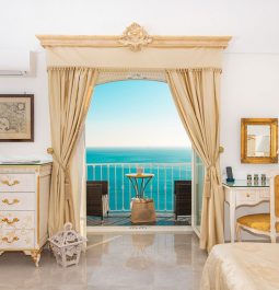 hotel suite with curtained balcony overlooking ocean