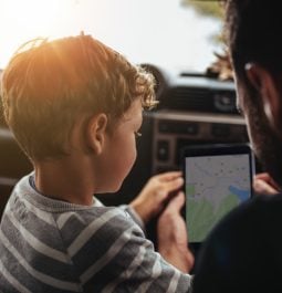 A Father and son plan their route of a road trip in their car using an app