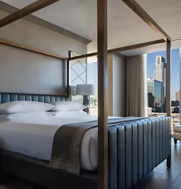 four poster bed with floor to ceiling windows overlooking city skyline
