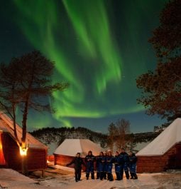guests enjoy the unique opportunity to watch the northern lights over a snowy resort in Norway