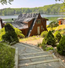 Cabin with stairs leading down to it and lake behind it