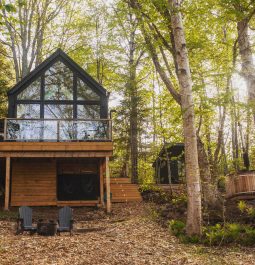 Exterior of the modern cabin in the forest with a hot tub