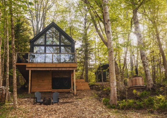 Exterior of the modern cabin in the forest with a hot tub